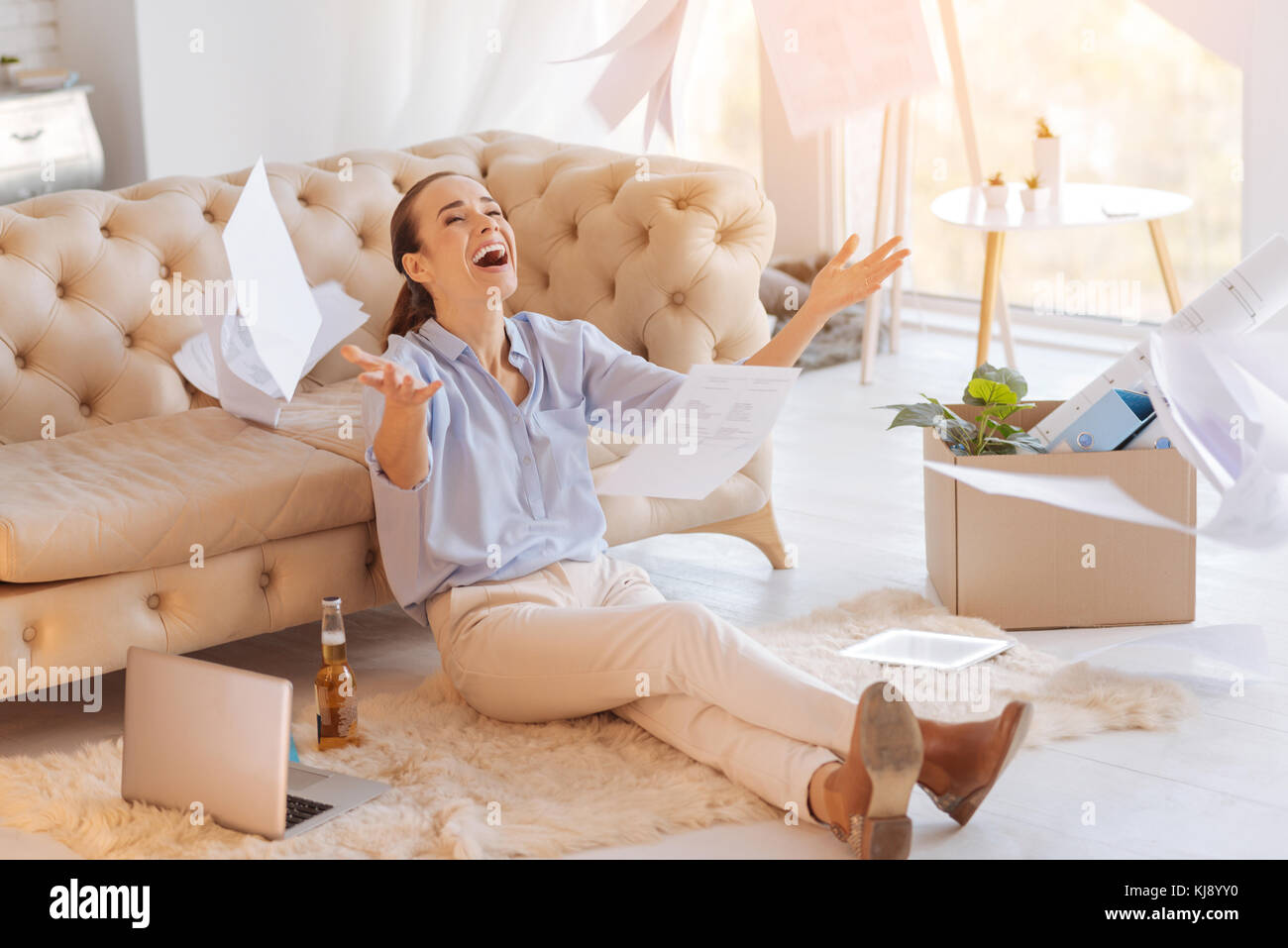 Gioiosa giovane donna gettando i documenti e sorridente Foto Stock