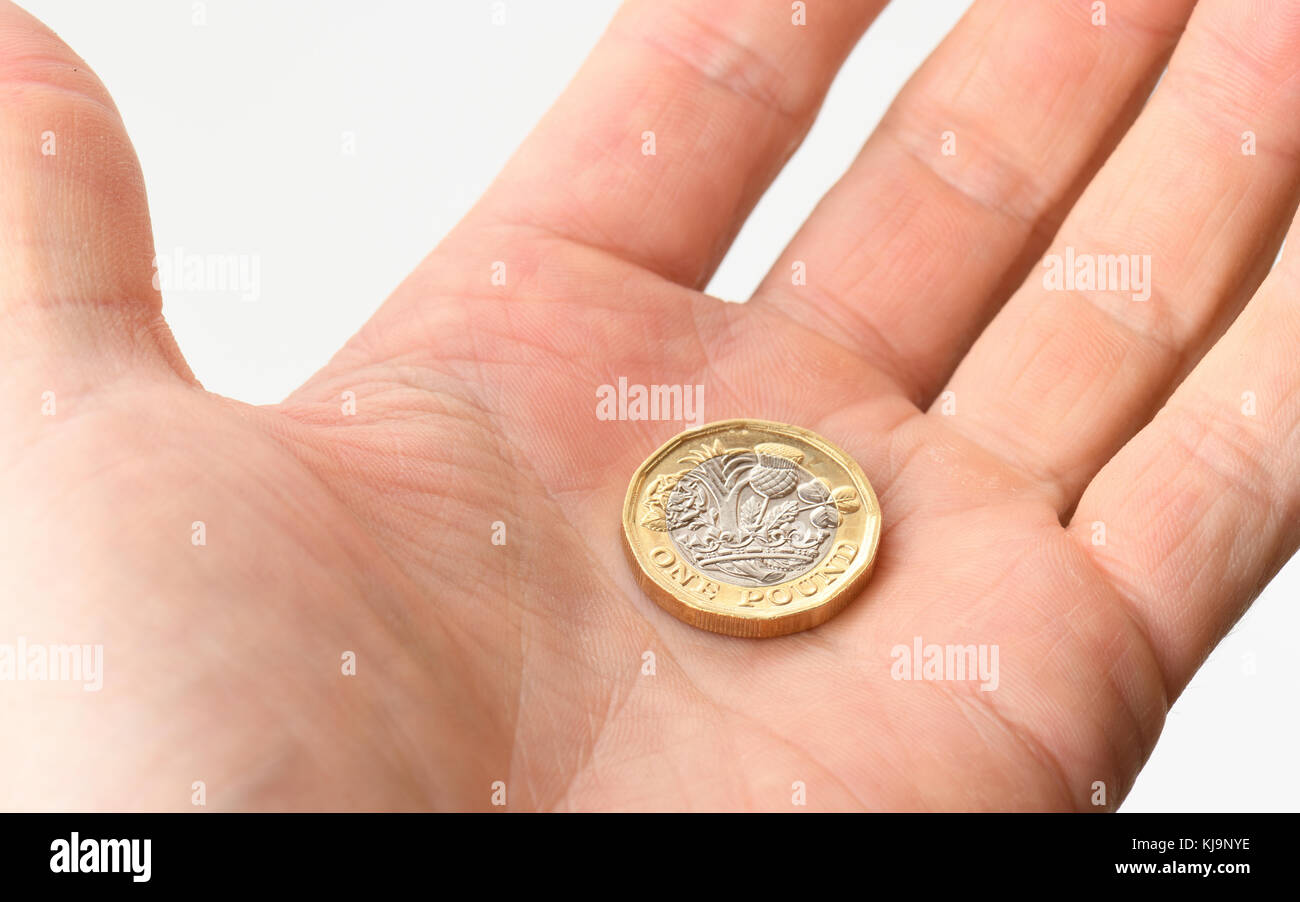 Una mano aperta che offre una moneta da sterlina Foto Stock