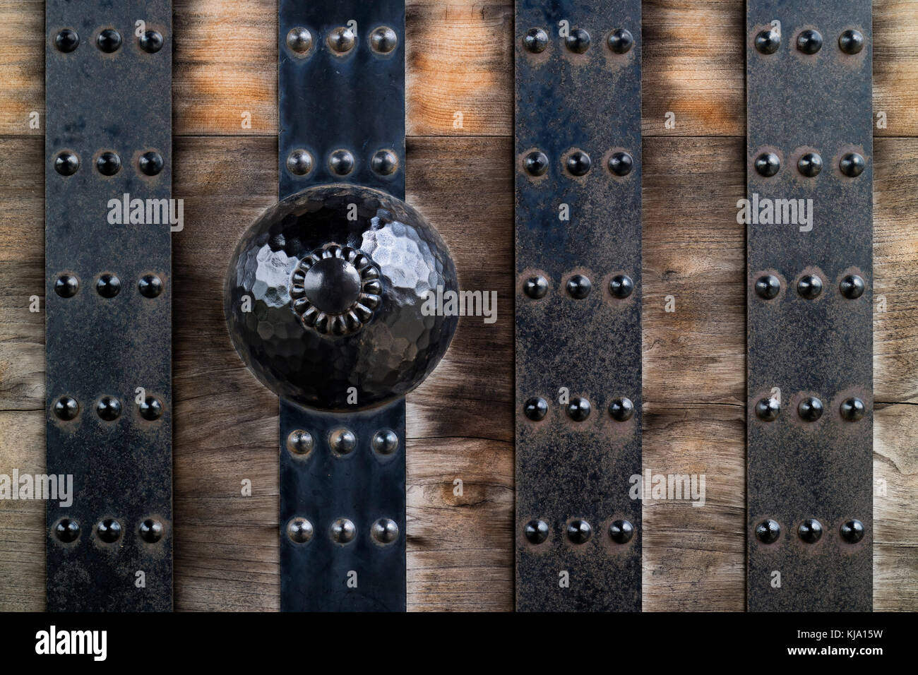 Le strisce metalliche ed ornamento su un vecchio weathered porta in legno Foto Stock