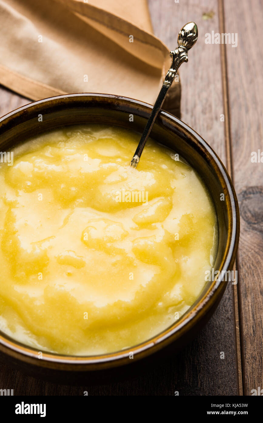 Desi ghee o burro chiarificato in vetro o rame contenitore o barattolo in ceramica con cucchiaio, il fuoco selettivo Foto Stock