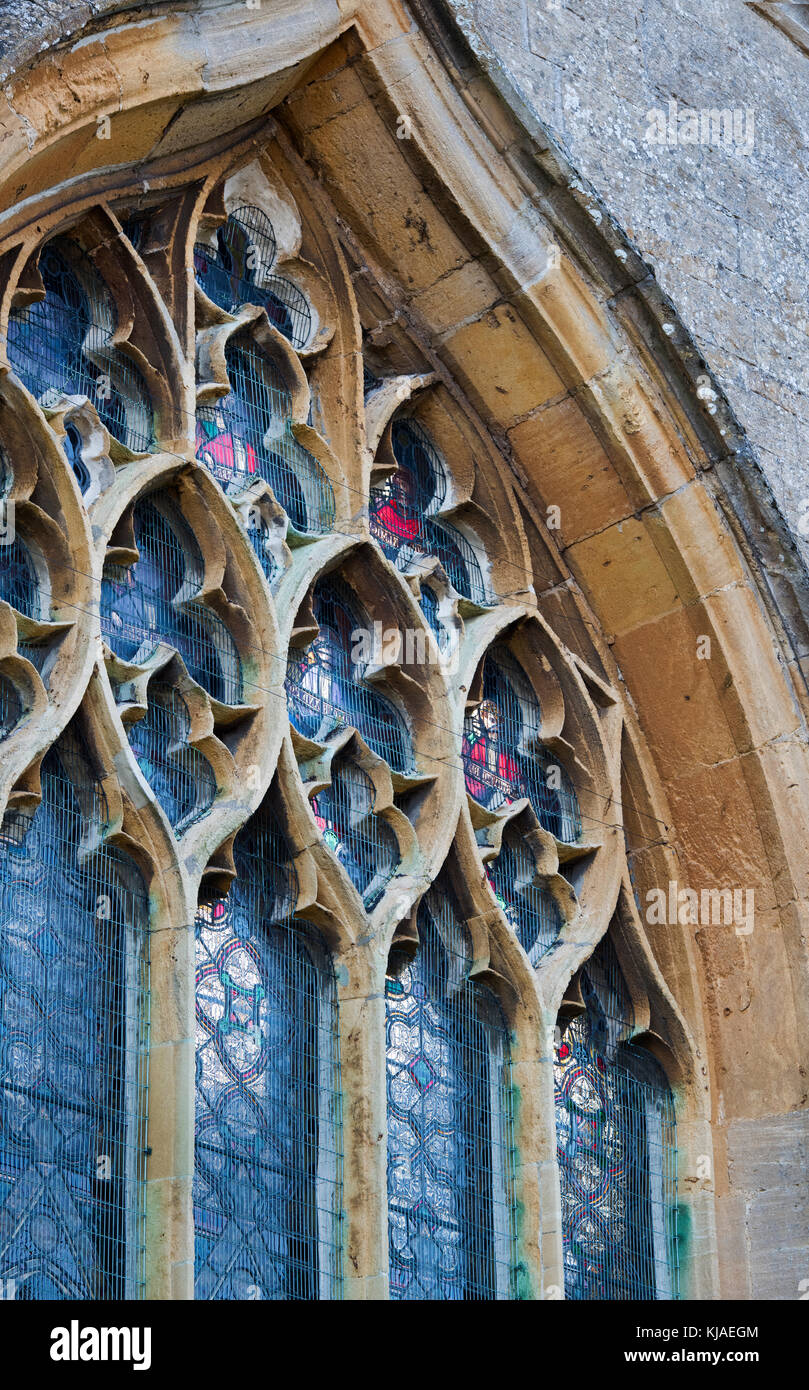 La mattina presto la luce del sole attraverso una finestra di vetro colorato dall'esterno della St Edward chiesa. Stow on the Wold, Gloucestershire, Cotswolds, Inghilterra Foto Stock