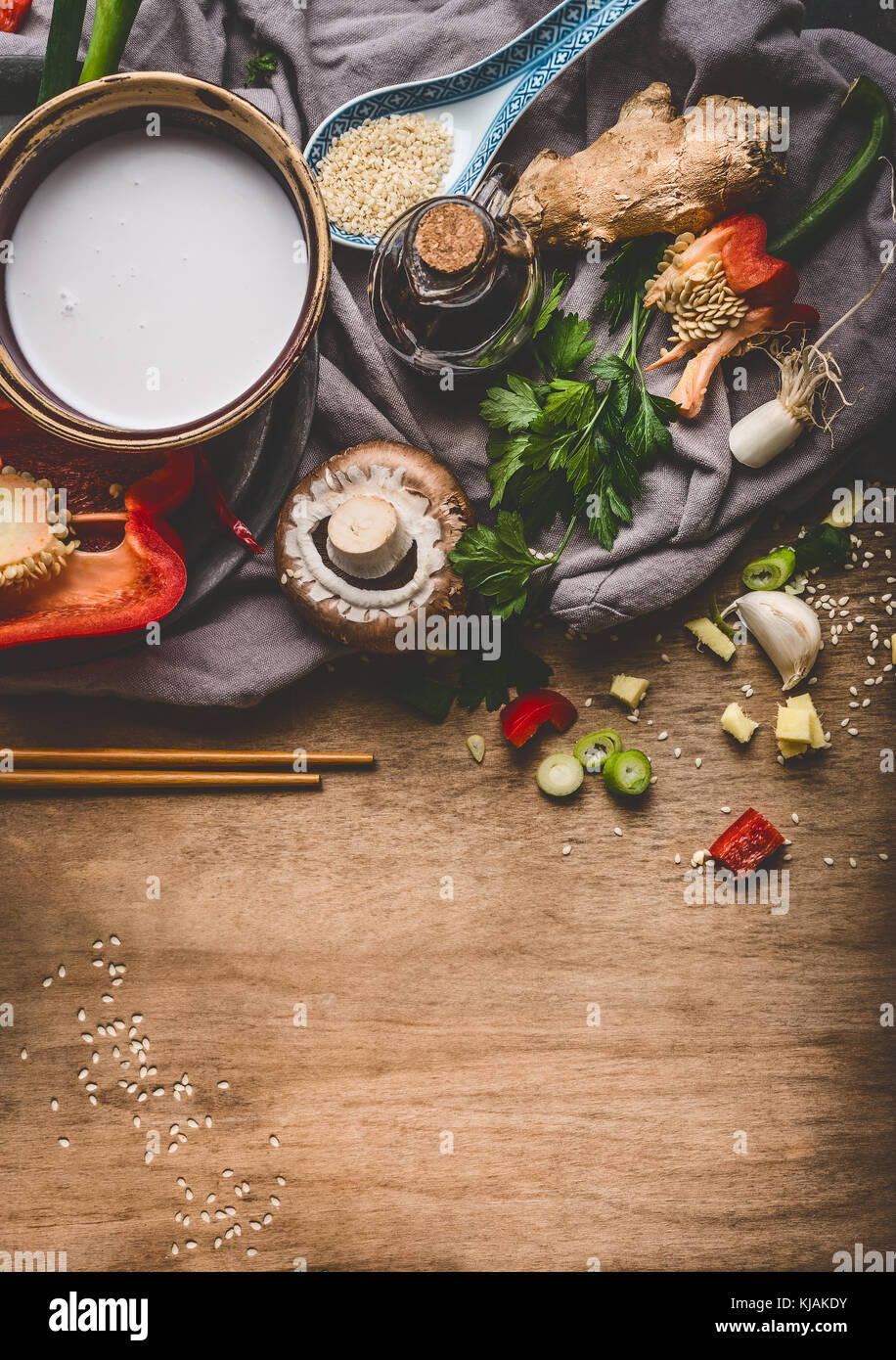 Vegetariano cucina asiatica ingredienti con un trito di verdure, latte di cocco, semi, spezie e bastoncini in legno rustico sfondo, vista dall'alto. Foto Stock