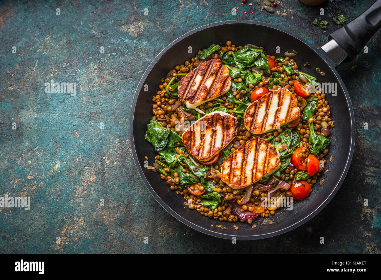 Cibo vegetariano concetto. sano piatto di lenticchie con spinaci e formaggio fritto in padella di cottura su sfondo rustico con ingredienti, vista dall'alto. Foto Stock
