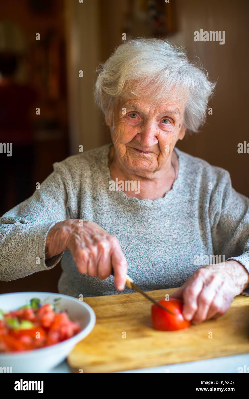 Ritratto di una donna anziana trita verdure per insalata. Foto Stock