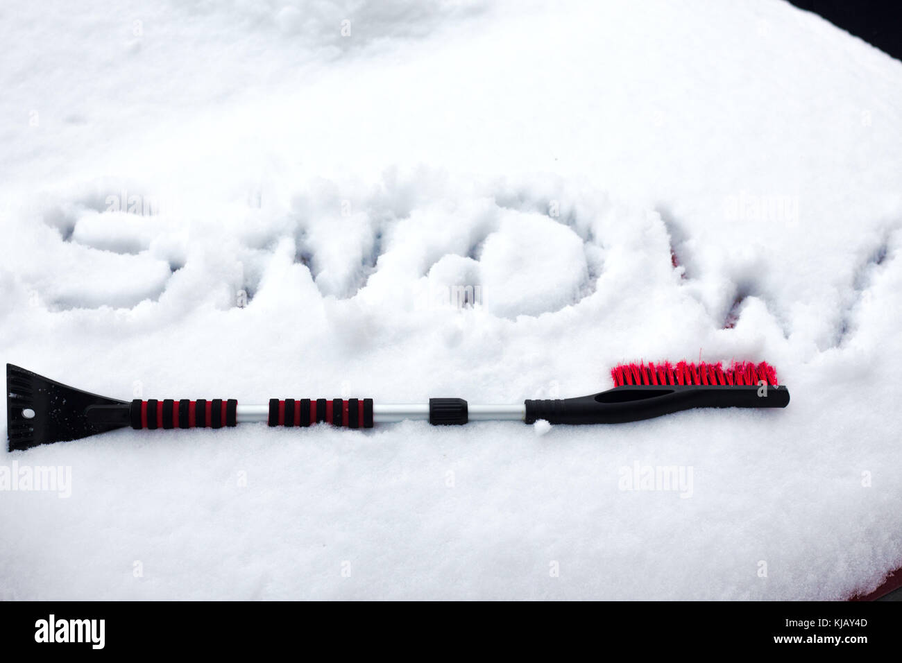 Mano nel guanto nero rimuove la neve da auto parabrezza in giornata invernale Foto Stock