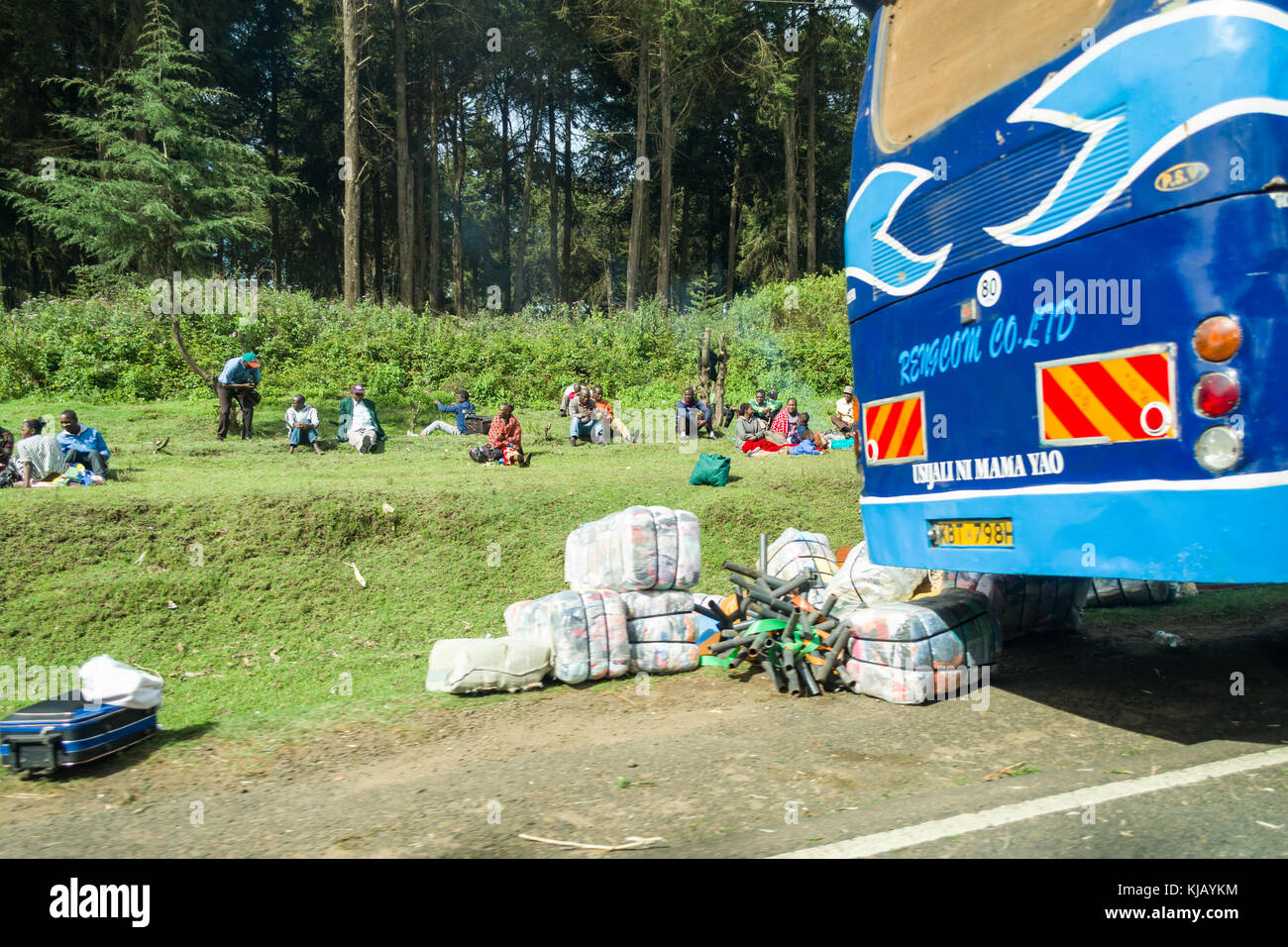I passeggeri provenienti da ripartiti autobus sedersi sul ciglio della strada in attesa che il veicolo possa essere fissato, Kenya, Africa orientale Foto Stock
