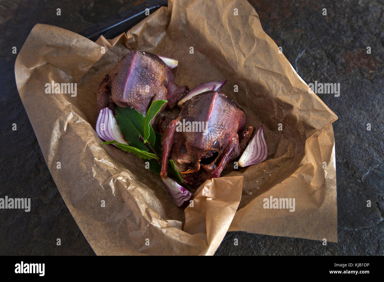 Forno pronto Faraona con cipolla rossa e foglie di alloro in pergamena di cottura Foto Stock