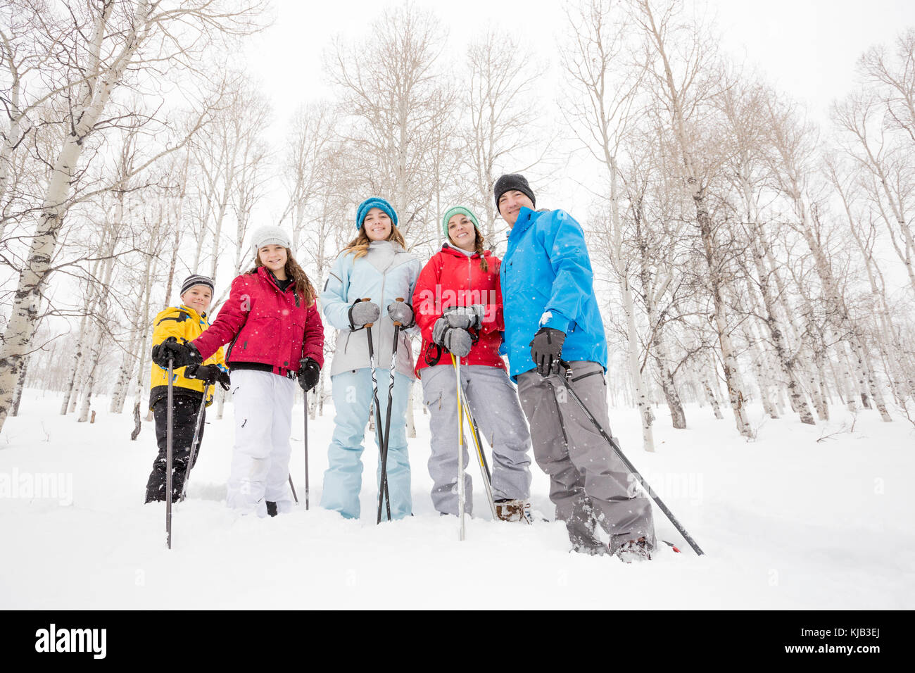 Ritratto di sorridente famiglia caucasica escursioni con le racchette da neve Foto Stock