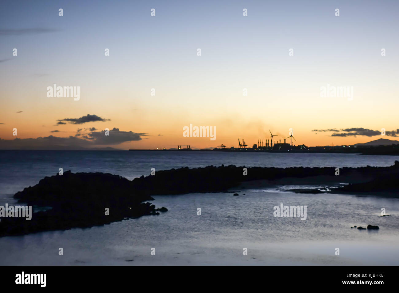LANZAROTE, SPAGNA-4 novembre 2017: Tramonto nella principale località turistica della Costa Teguise con la centrale elettrica dell'isola per l'approvvigionamento energetico sul retro Foto Stock