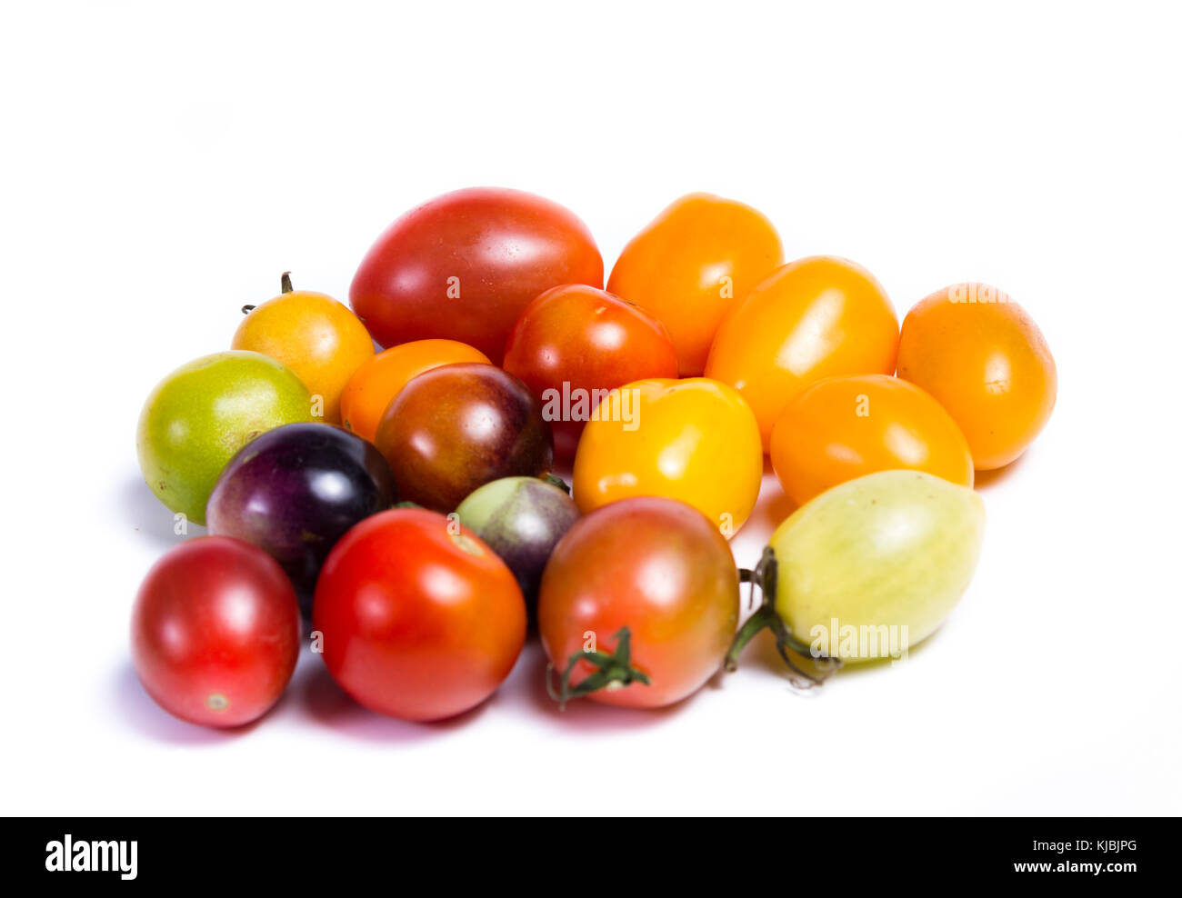 Cluster di piccoli pomodori ciliegia in una varietà di colori isolati su sfondo bianco Foto Stock