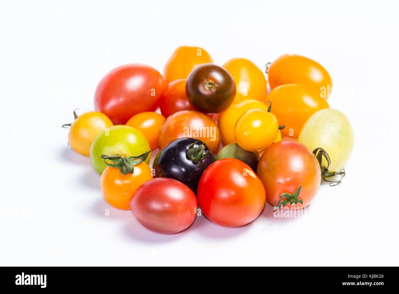 Cluster di piccoli pomodori ciliegia in una varietà di colori isolati su sfondo bianco Foto Stock