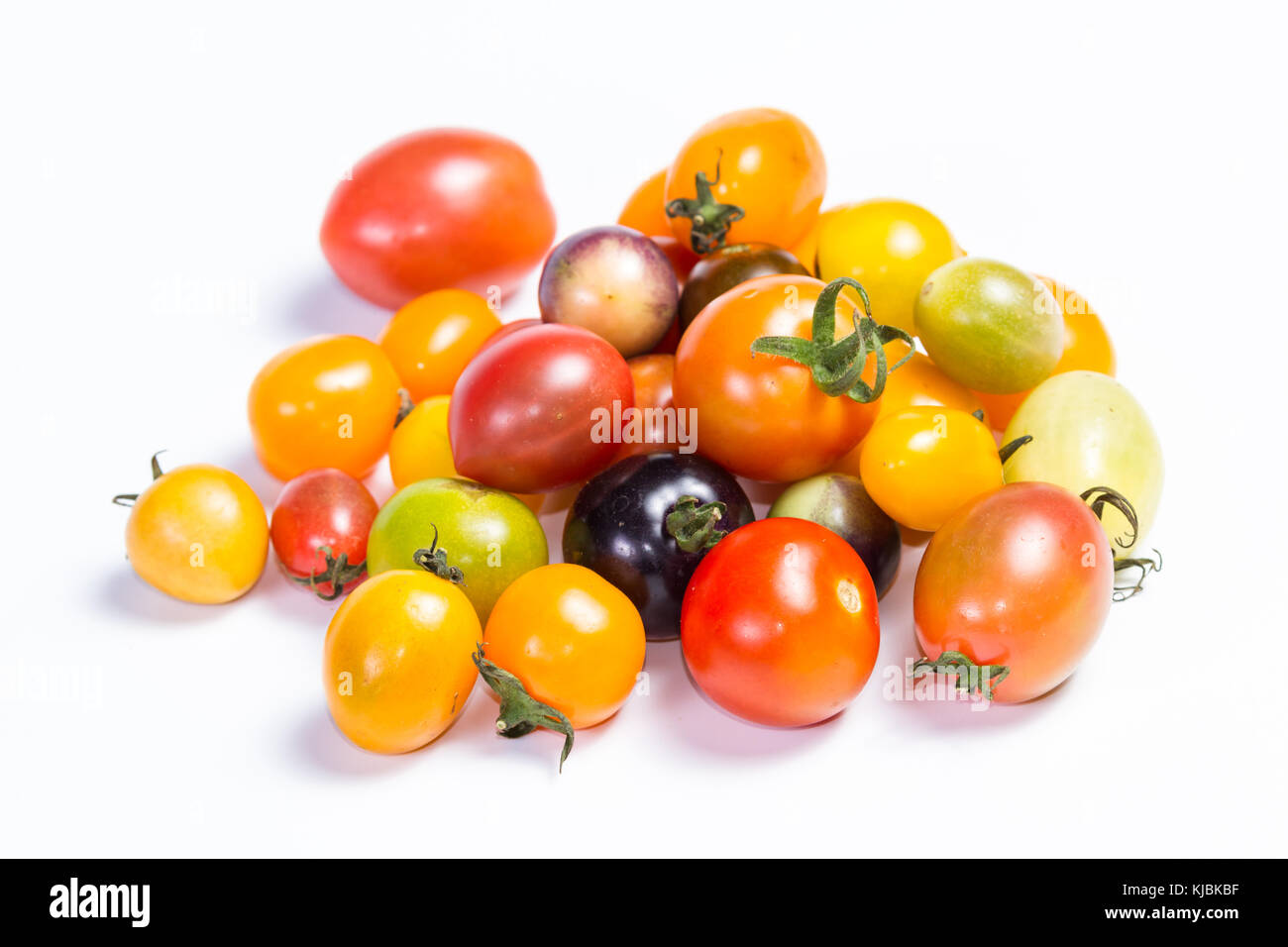 Cluster di piccoli pomodori ciliegia in una varietà di colori isolati su sfondo bianco Foto Stock