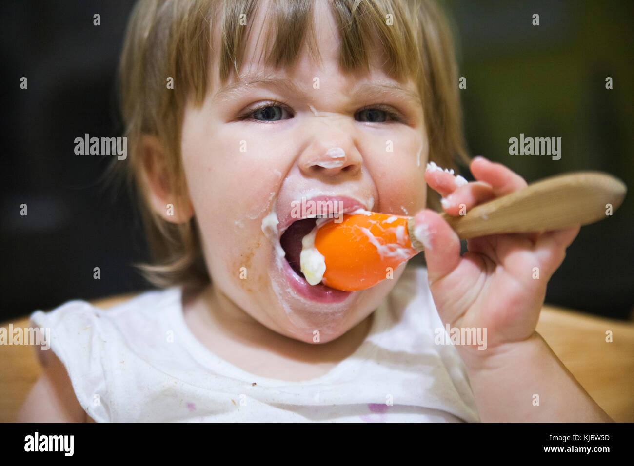 Confuso bambino mangiare con il cucchiaio Foto Stock
