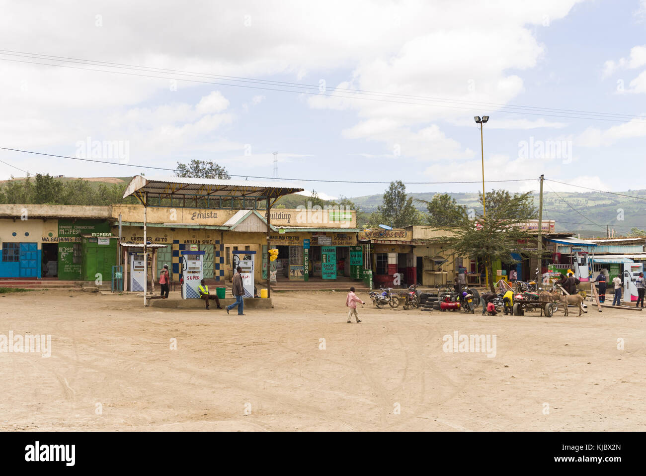 Una piccola stazione di benzina tra negozi con la gente camminare al di fuori, Kenya, Africa orientale Foto Stock