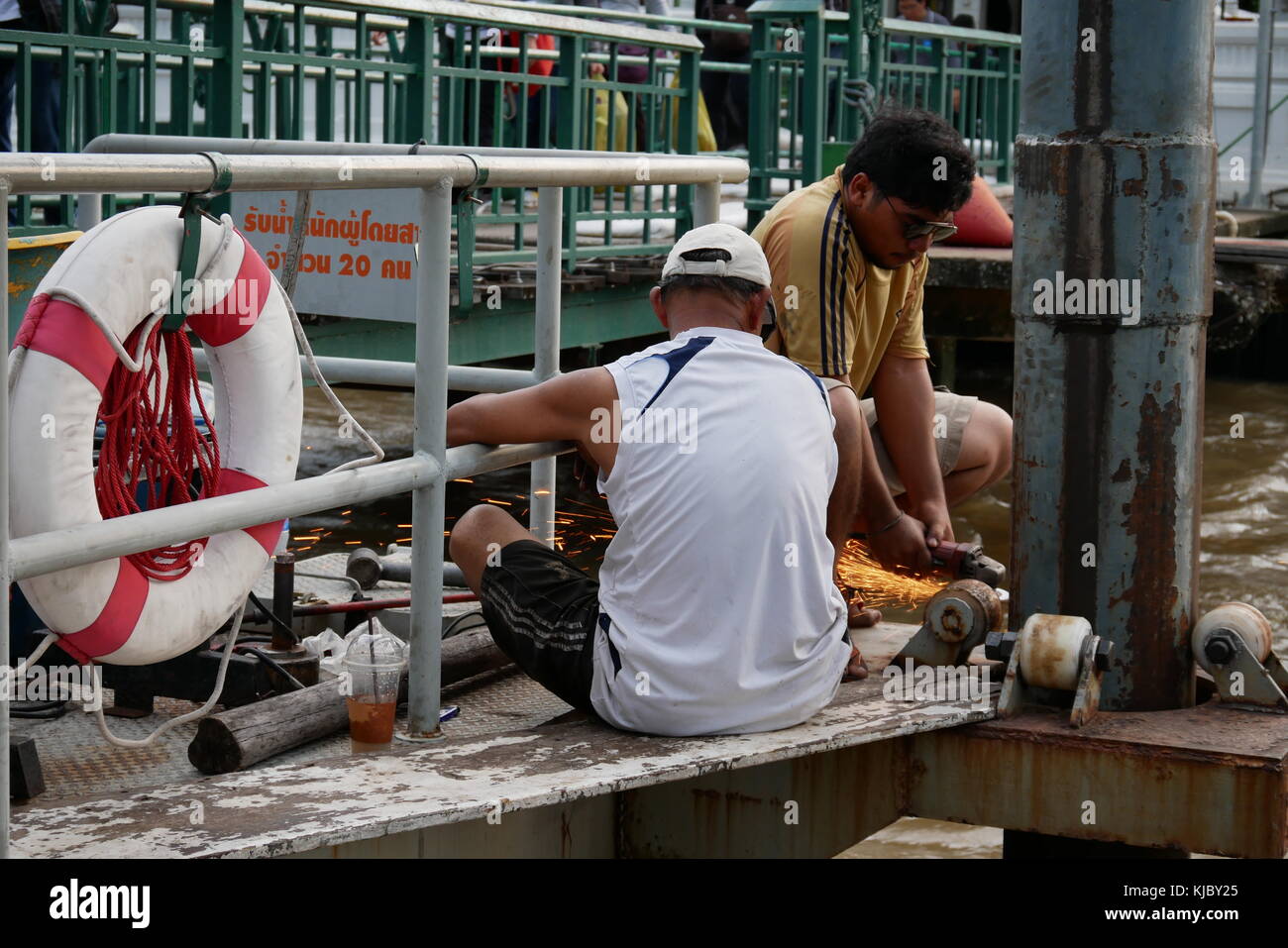 Uomini al lavoro su un pilastro del molo piattaforma in Thonburi lungo il Fiume Chao Praya river in Bangkok. Foto Stock