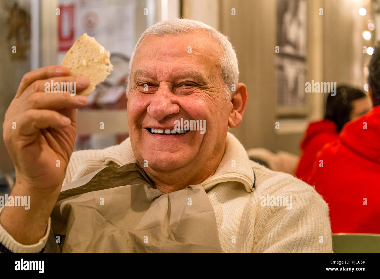 Felice vecchio uomo sorridente mentre a mangiare una fetta di pane in un ristorante Foto Stock