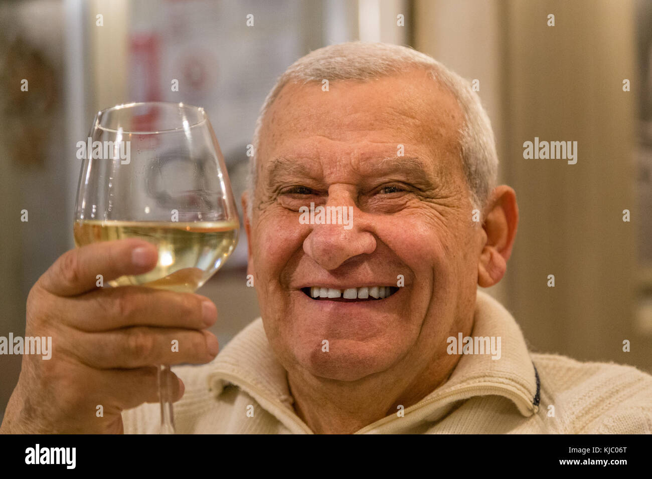 Felice vecchio uomo sorridente e di bere il vino bianco in un ristorante Foto Stock