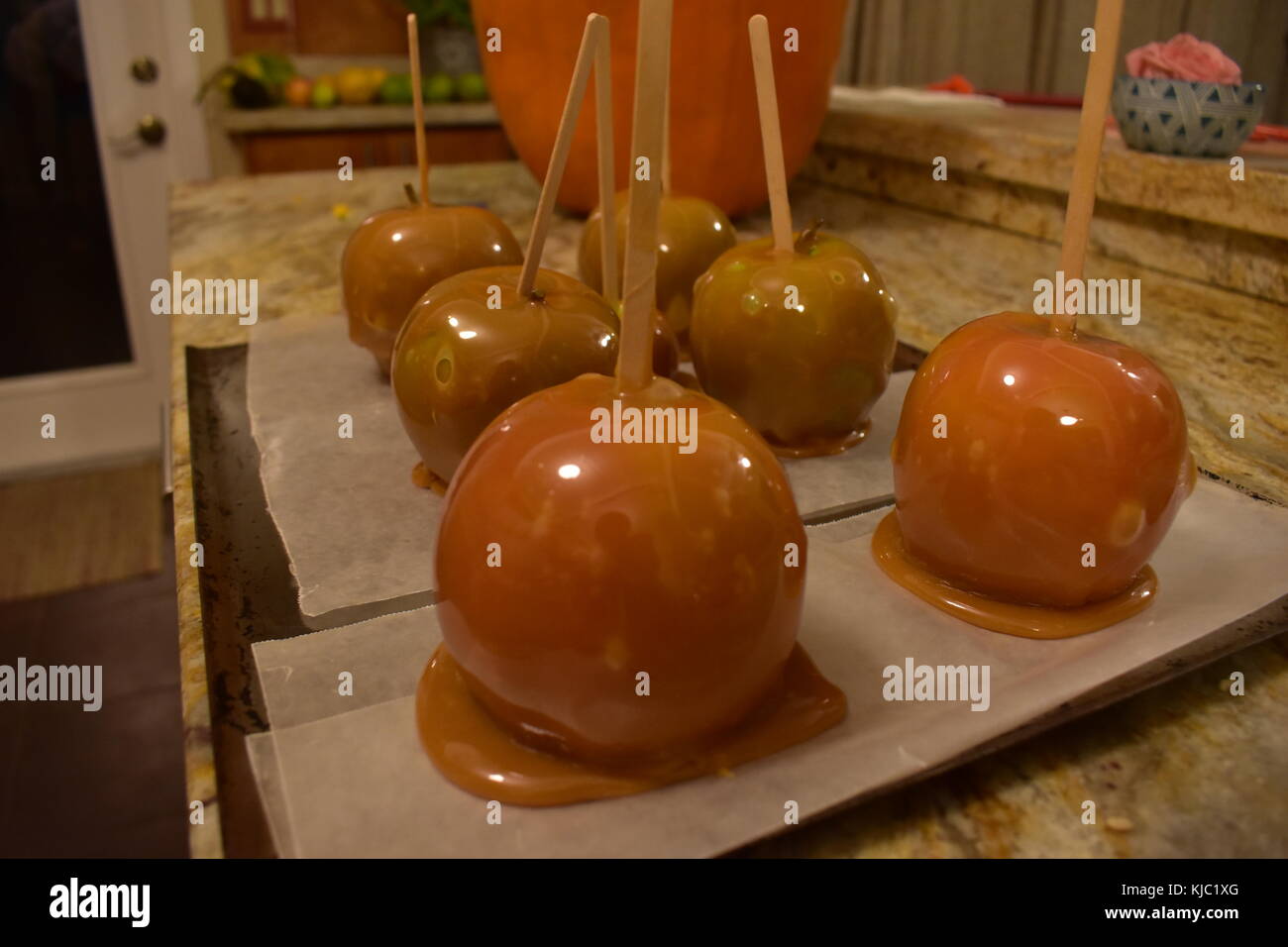 Appena sfornati caramello mele fatte con fuso caramello seduto davanti a un scolpito la zucca di Halloween. Foto Stock