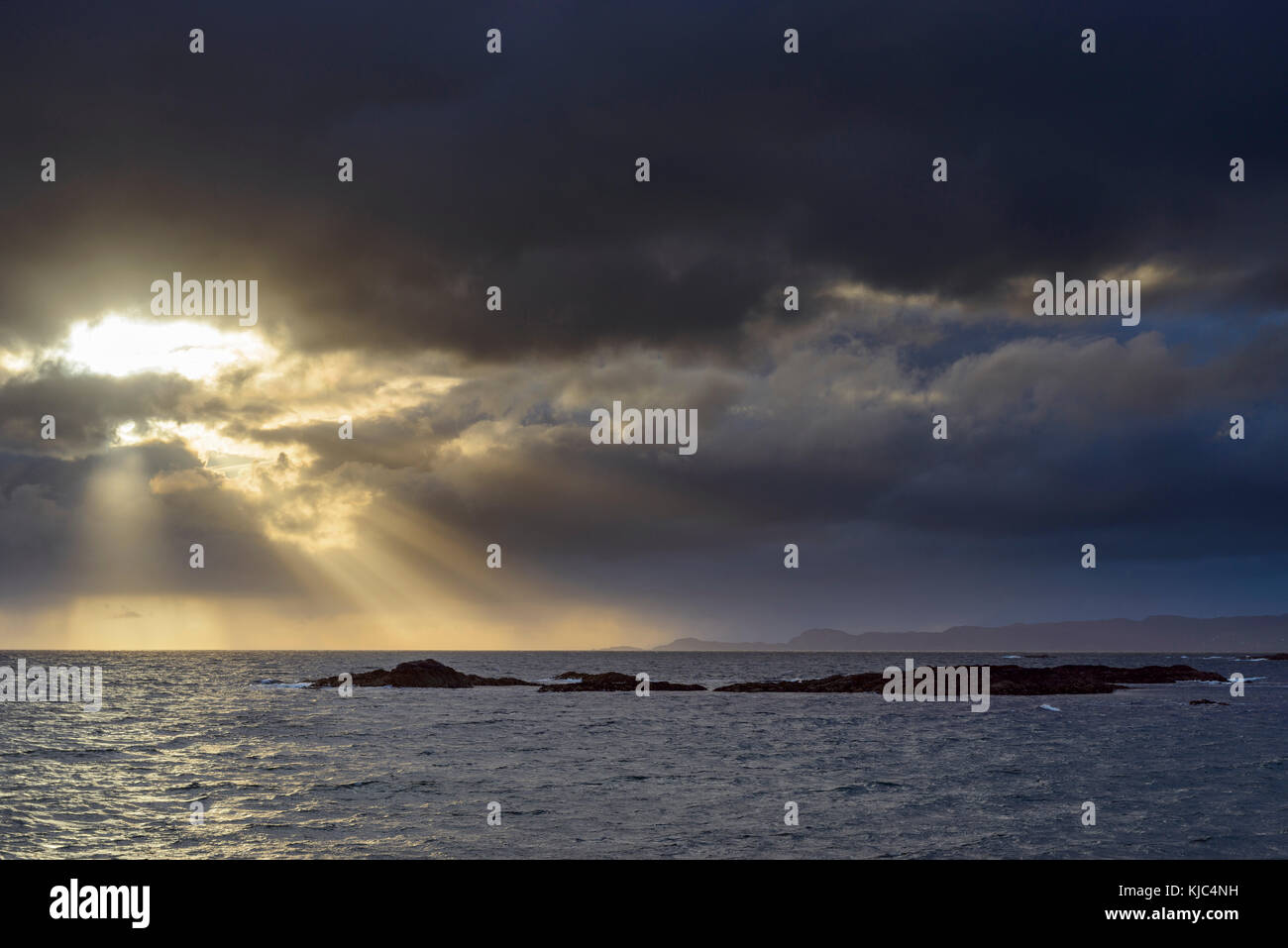 Sole che splende attraverso le nuvole tempeste all'alba lungo la costa scozzese a Mallaig in Scozia, Regno Unito Foto Stock