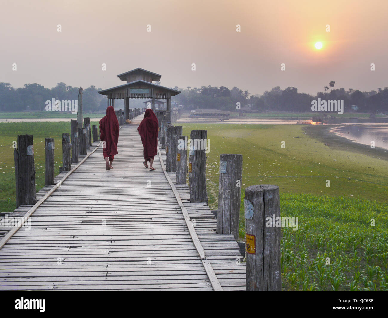 I monaci birmani attraversano il ponte U Bein sopra il lago Taungthaman ad Amarapura al tramonto. U Bein Bridge è il ponte in teak più lungo del mondo, 1,2 km Foto Stock
