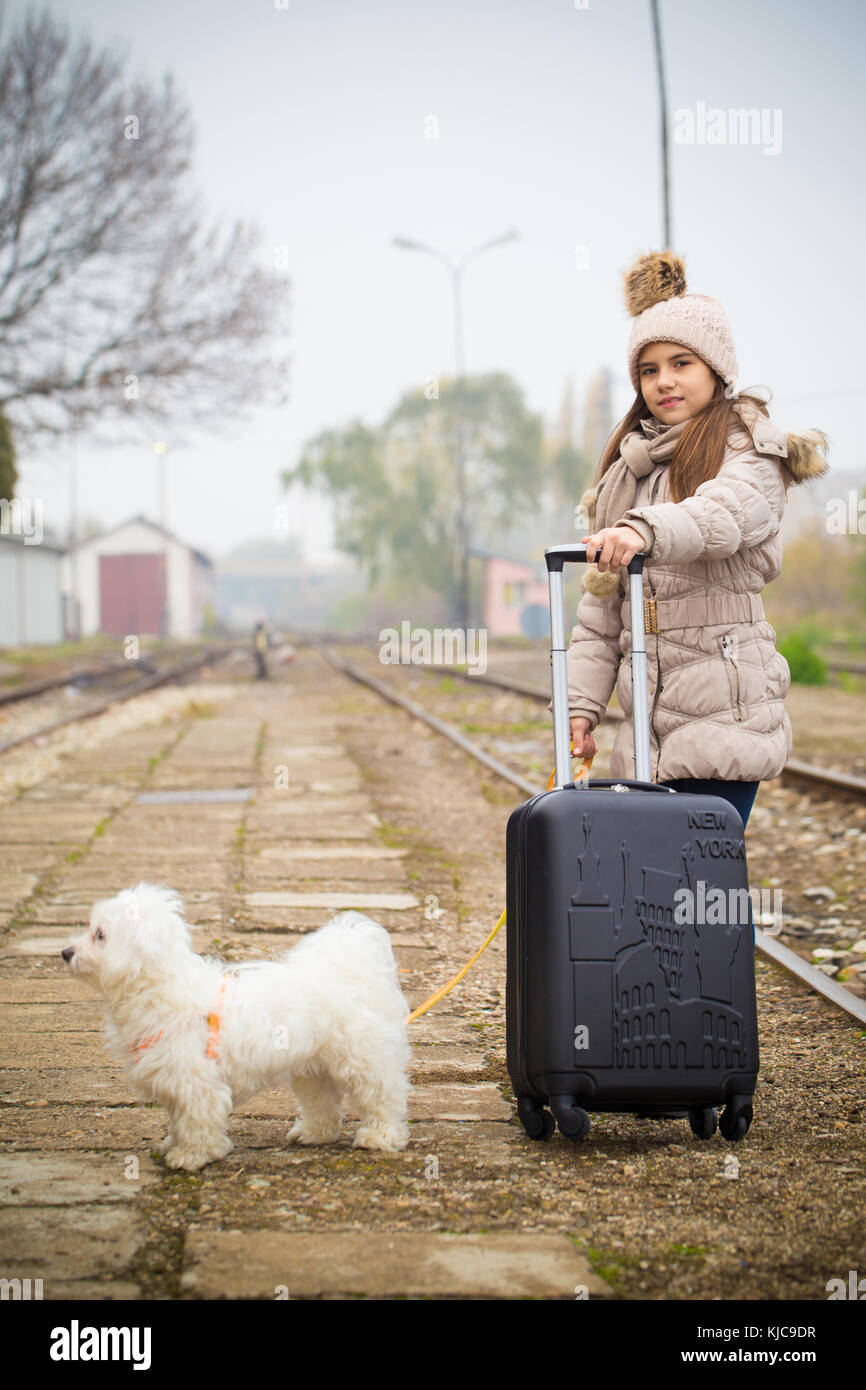Felice bambina con il suo cane e la valigia in una stazione ferroviaria. il  capretto con cane in attesa del treno e felice circa il viaggio Foto stock  - Alamy