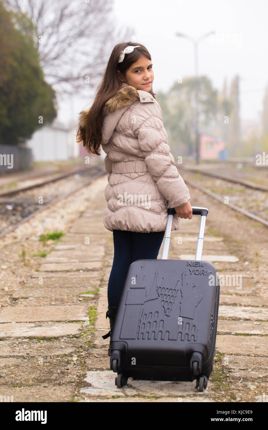 Bambina con una valigia, in piedi presso la stazione in attesa di un treno  Foto stock - Alamy