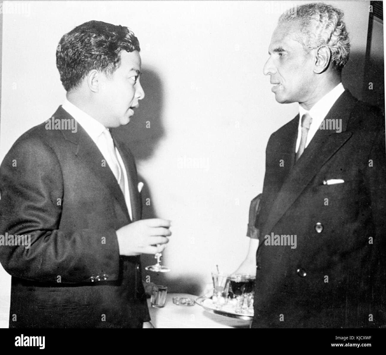 Questa fotografia cattura il momento in cui V.K. Krishna Menon, un diplomatico indiano, parla con il principe Norodom Sihanouk della Cambogia. L'interazione probabilmente riflette discussioni politiche o relazioni diplomatiche tra India e Cambogia durante il loro periodo di fidanzamento. Foto Stock