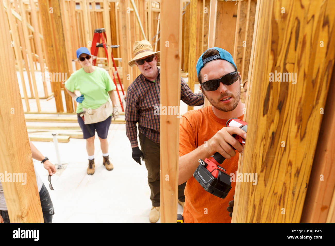 Volunteer mediante trapano a sito in costruzione Foto Stock