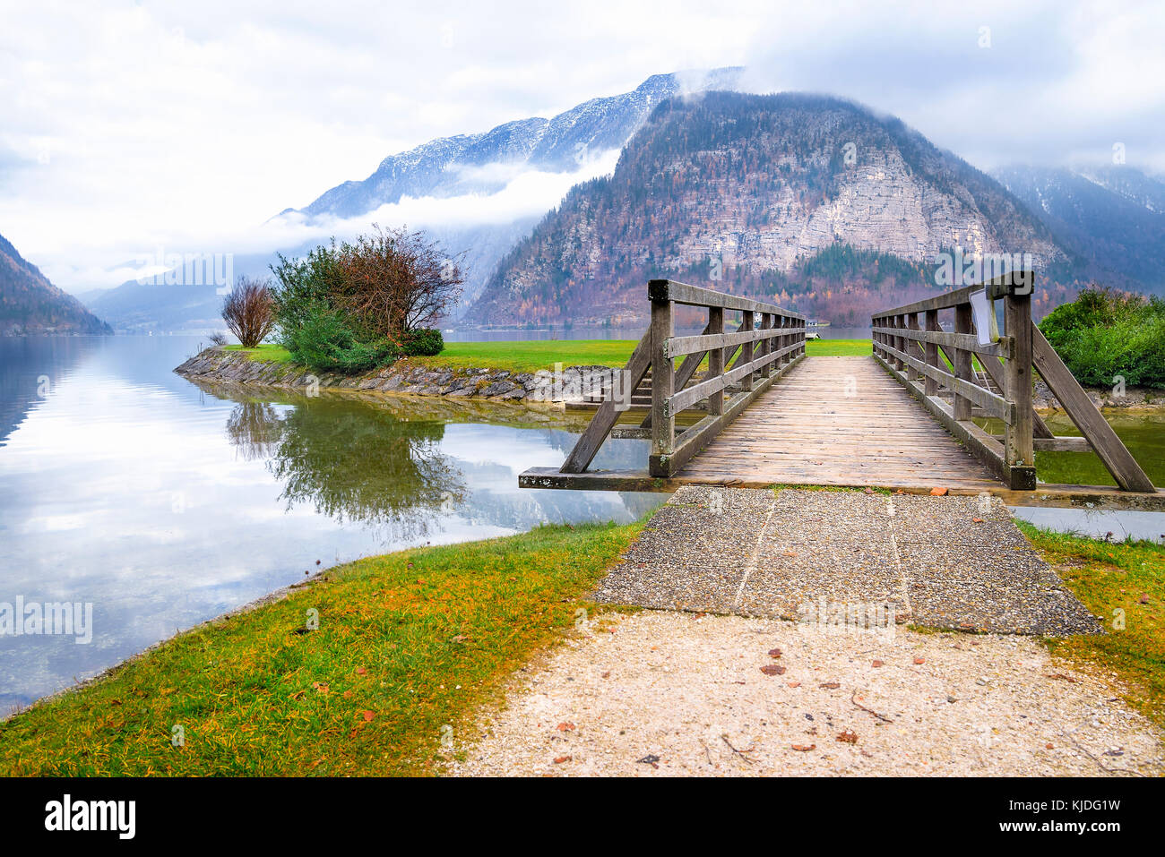 Nel tardo autunno il paesaggio alpino con le montagne del Dachstein, il lago hallstatter e un ponte di legno per la piccola isola del lago, nella città di Hallstatt. Foto Stock