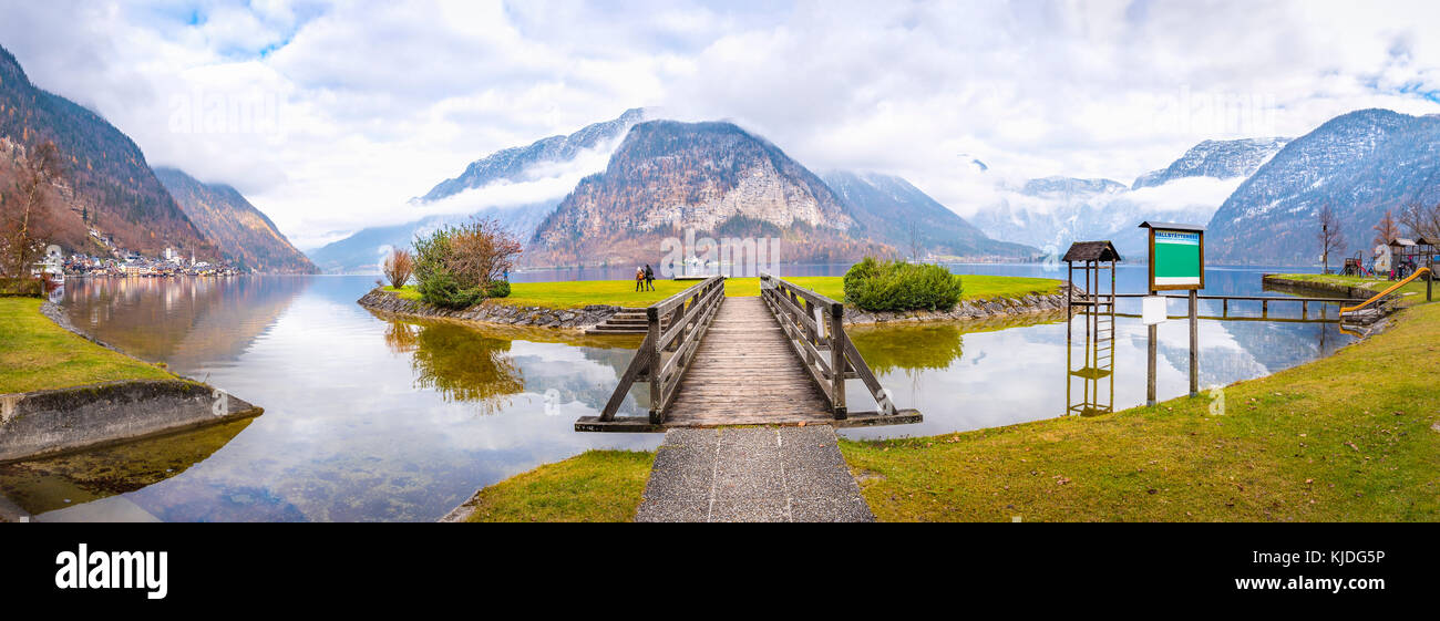 Il tardo autunno panorama con il lago hallstatter, le alpi austriache, l'isola del lago e un ponte di legno per gli accessi, nella città di Hallstatt Foto Stock