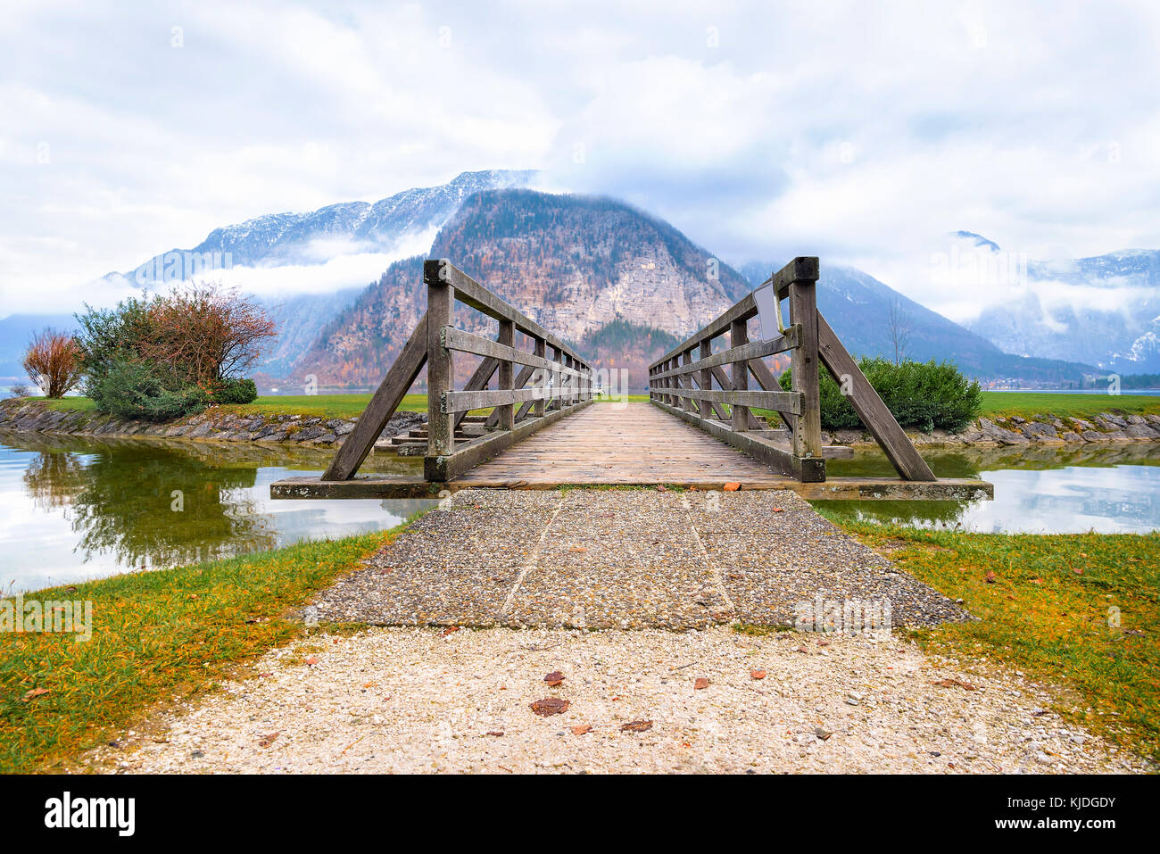 Scenario idilliaco con un vecchio rustico ponte sul lago hallstatter, alla fine del quale i fedeli laici i monti Dachstein, dall' Austria Foto Stock