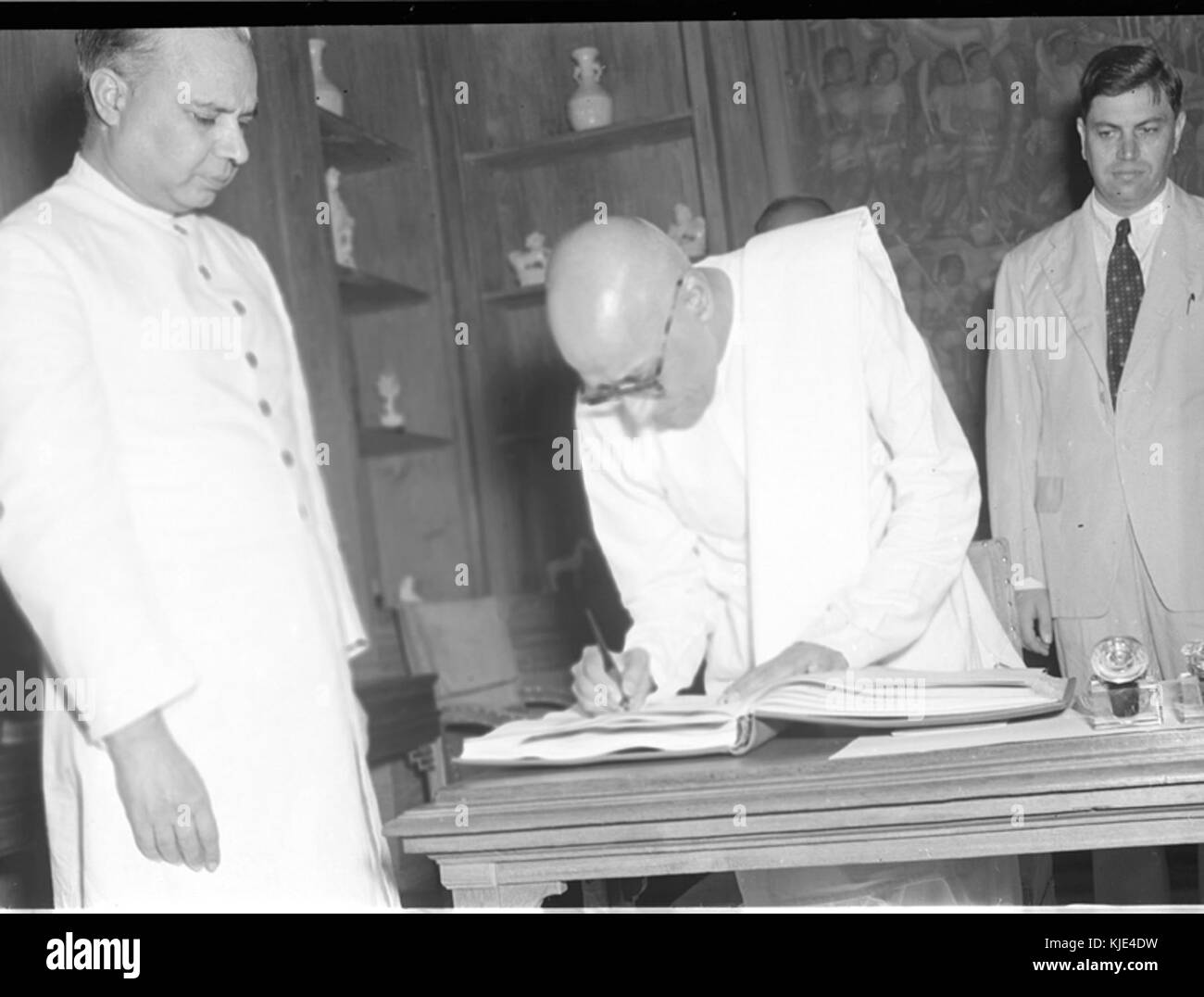 C. Rajagopalachari firma il registro dopo aver prestato giuramento di ufficio come un Gabinetto del Ministro Foto Stock