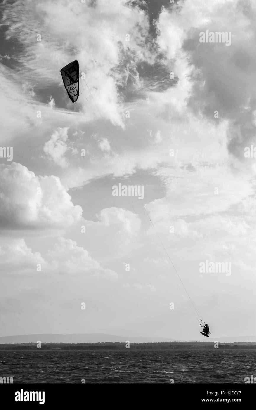 Un uomo a volare con un kite surf sul lago, con un profondo cielo nuvoloso sullo sfondo Foto Stock