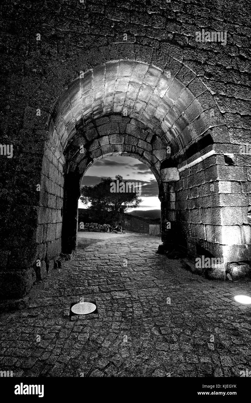 Porta cittadina medievale illuminata notturna con vicolo lastricato di ciottoli Foto Stock