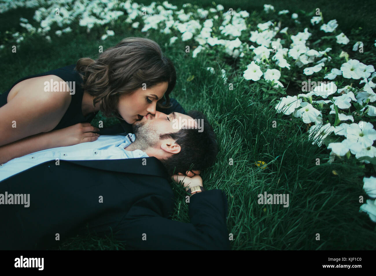 Coppia caucasica posa in erba kissing Foto Stock