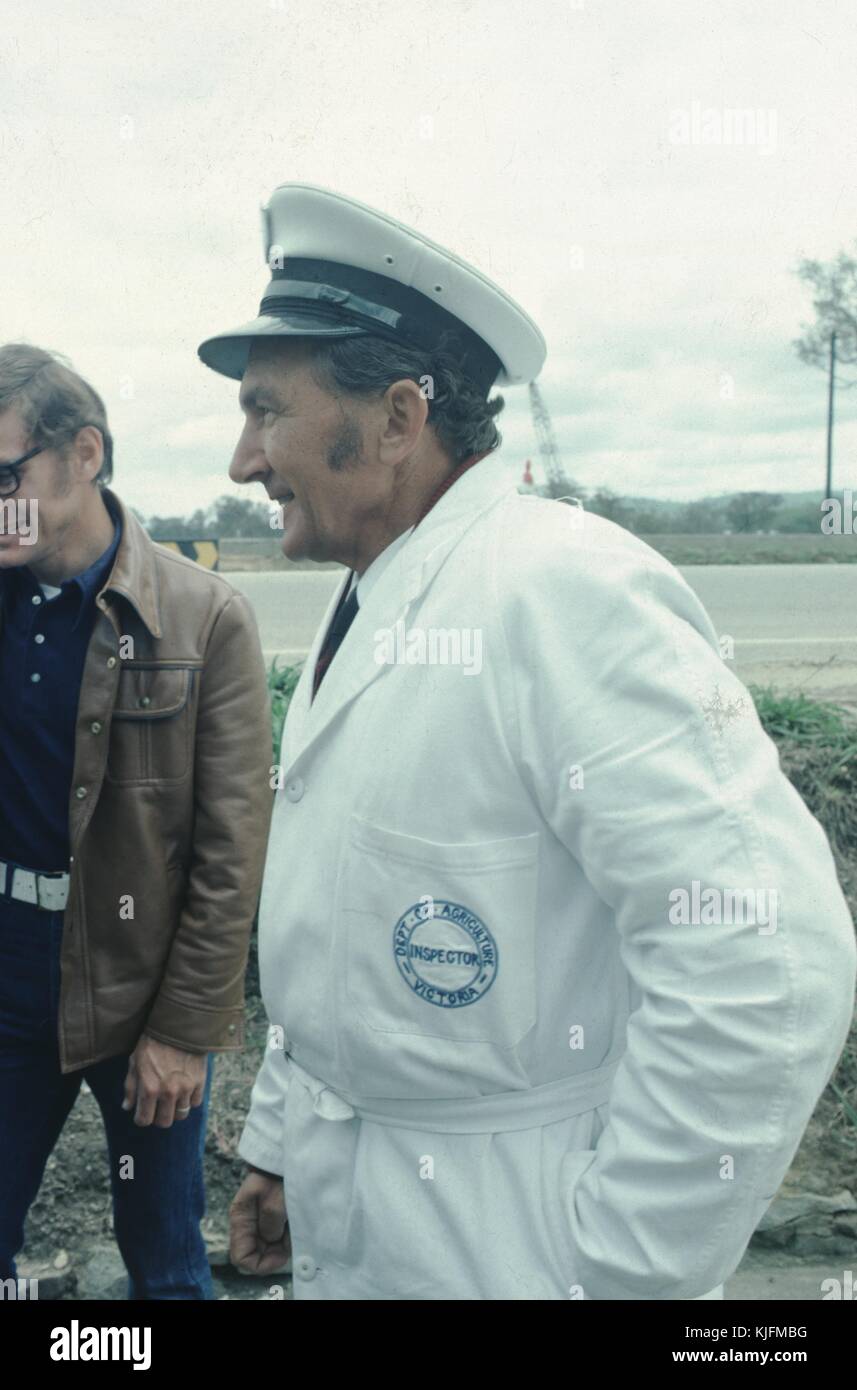 Ispettore del Dipartimento dell'Agricoltura in tuta bianca, ritratto di profilo in una fattoria, sorridente, Victoria, Canada, 1965. Foto Stock