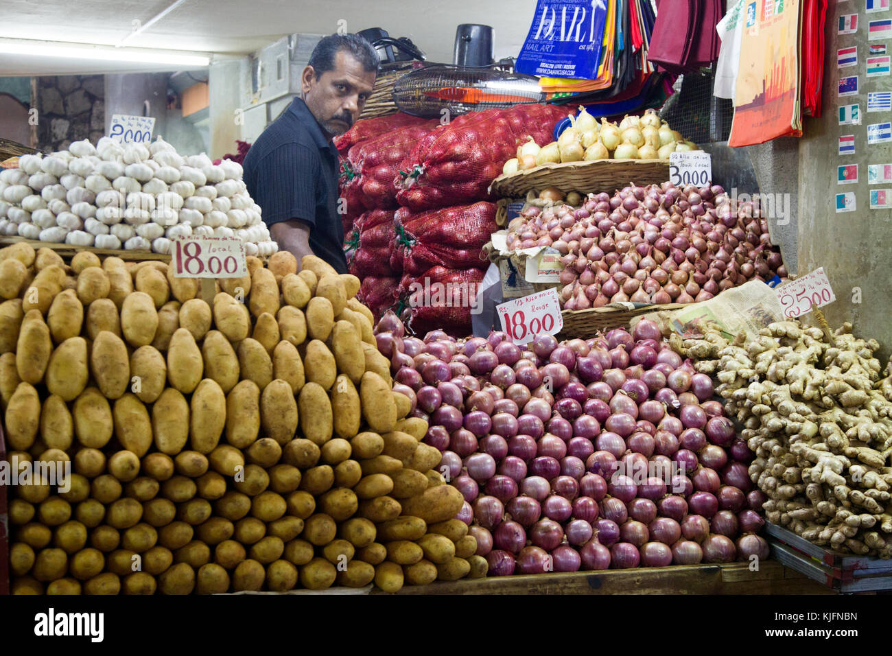 Venditore a vendere verdure al suo mercato in stallo il mercato centrale di port louis, Mauritius, africa. Foto Stock