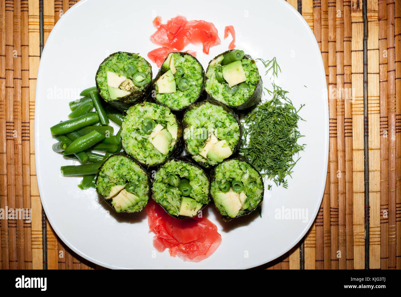 Crudo fresco piatto di cibo verde rotoli di foglie di uva con ripieno di verdure su piastra bianca sulla stuoia di paglia. vista dall'alto. Foto Stock