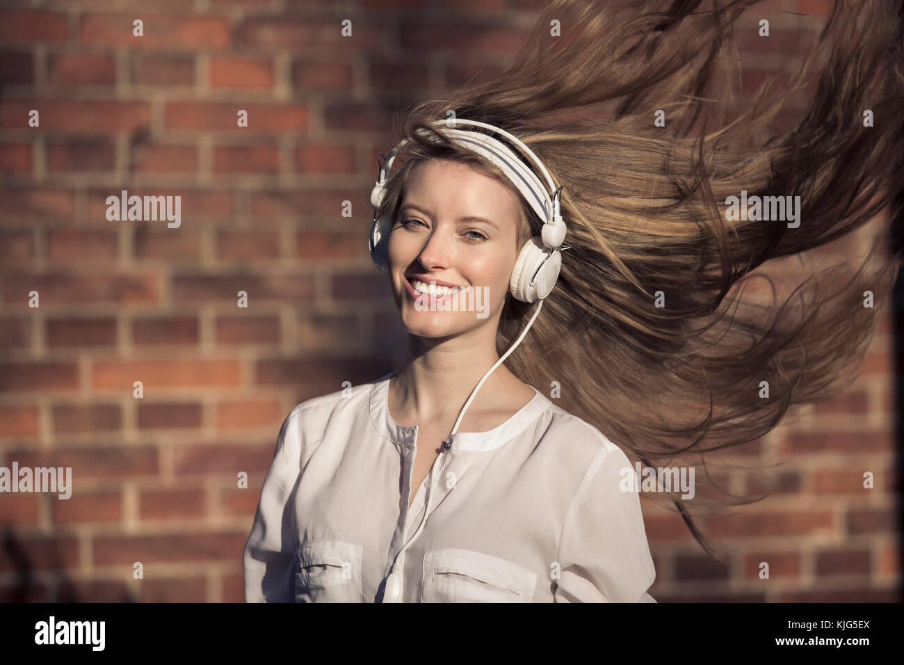 Ritratto di donna felice con le cuffie e i capelli di soffiatura Foto Stock