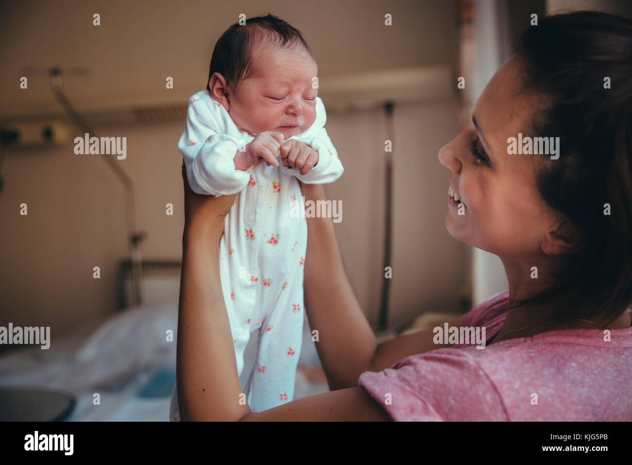 Felice madre mentre tiene il suo neonato in ospedale Foto Stock