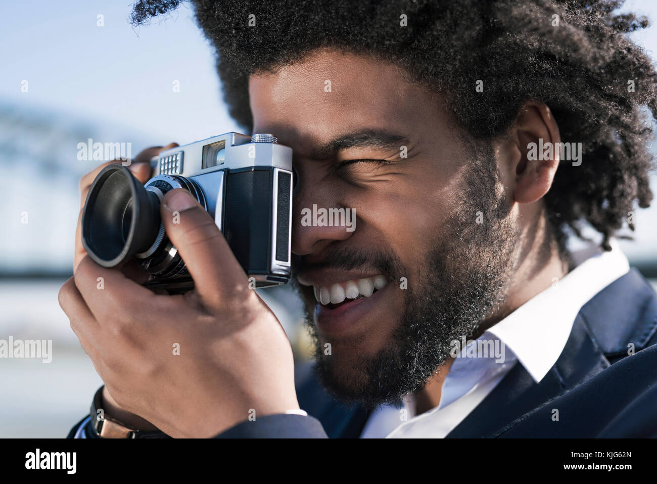 Close-up di uomo sorridente di scattare una foto con una fotocamera vintage Foto Stock