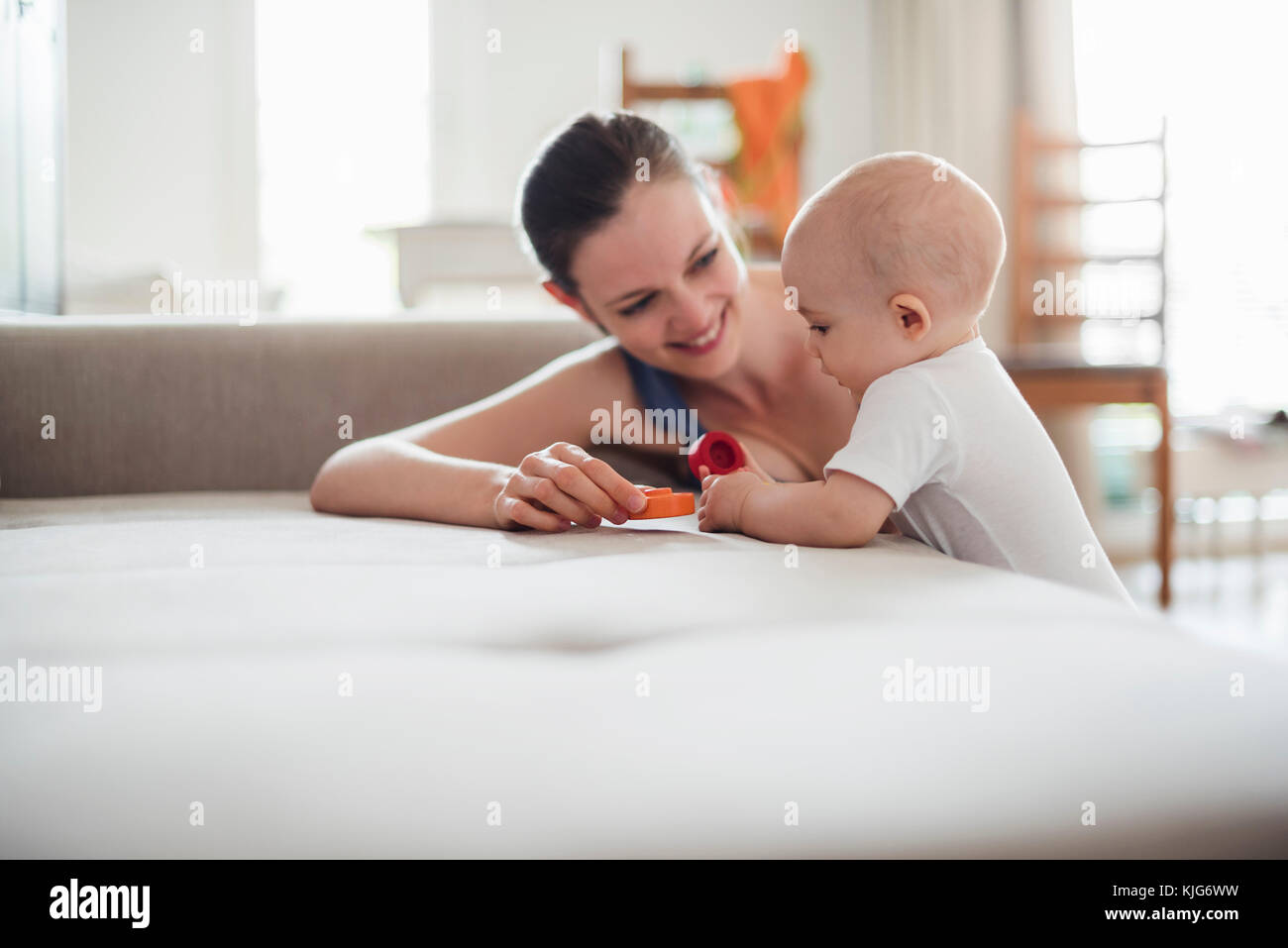 Bambina con la madre a giocare sul lettino a casa Foto Stock