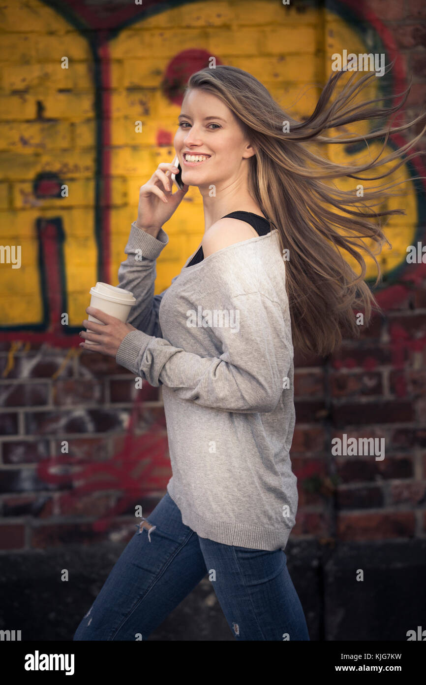 Ritratto di donna ridere con caffè per andare al telefono Foto Stock