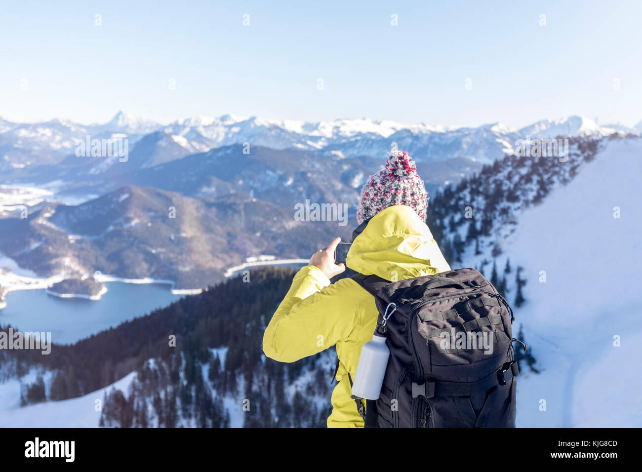 In Germania, in Baviera, Alpi escursionista con zaino in riva al lago di Walchen prendendo immagini dello smartphone Foto Stock