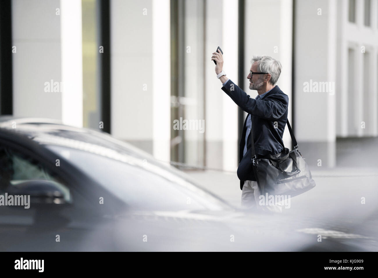 Grey-haired imprenditore di chiamare un taxi in città Foto Stock