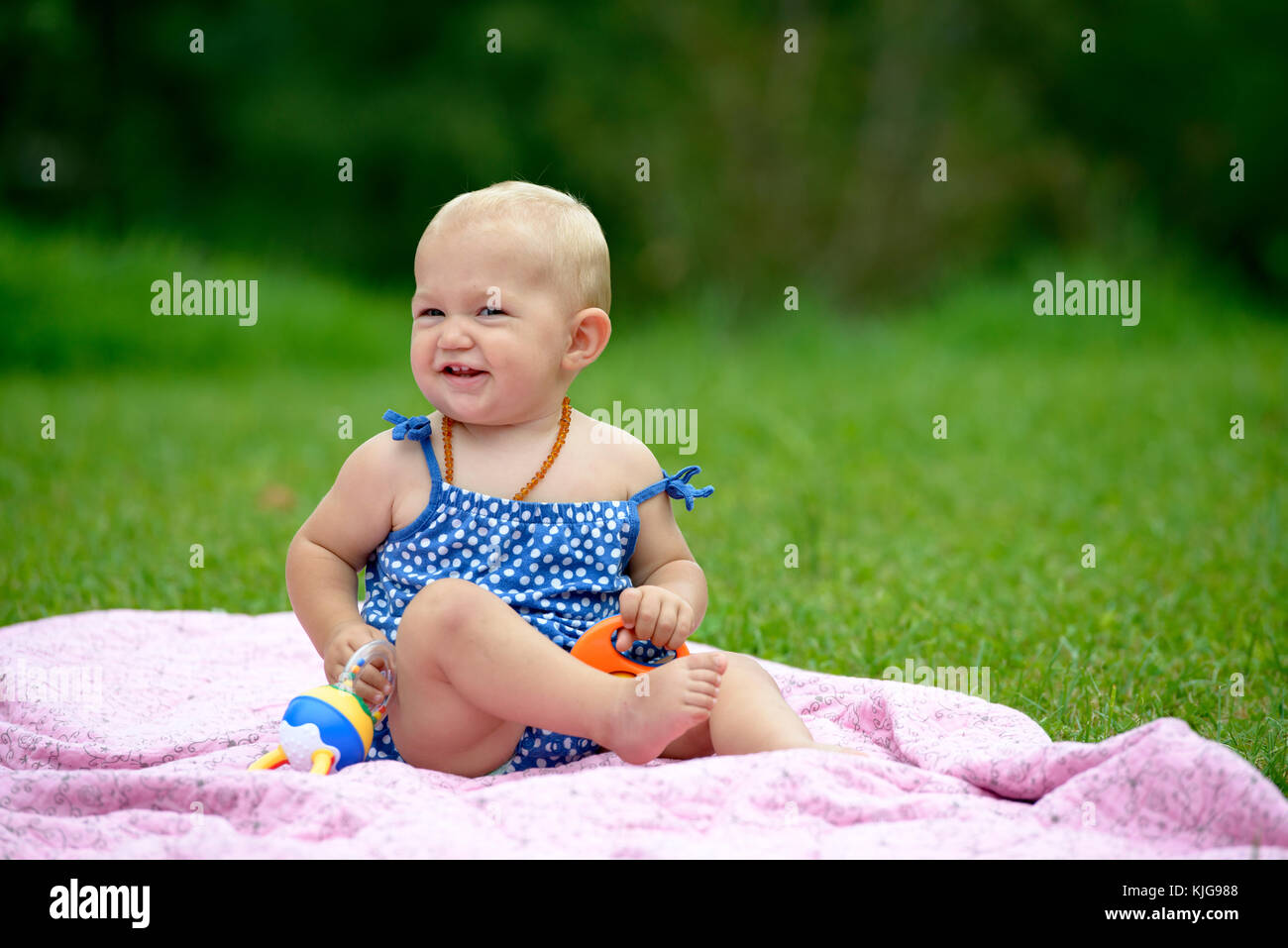 Kleines Mädchen sitzt auf ihrer Krabbeldecke im Grünen, Bayern, Deutschland Foto Stock