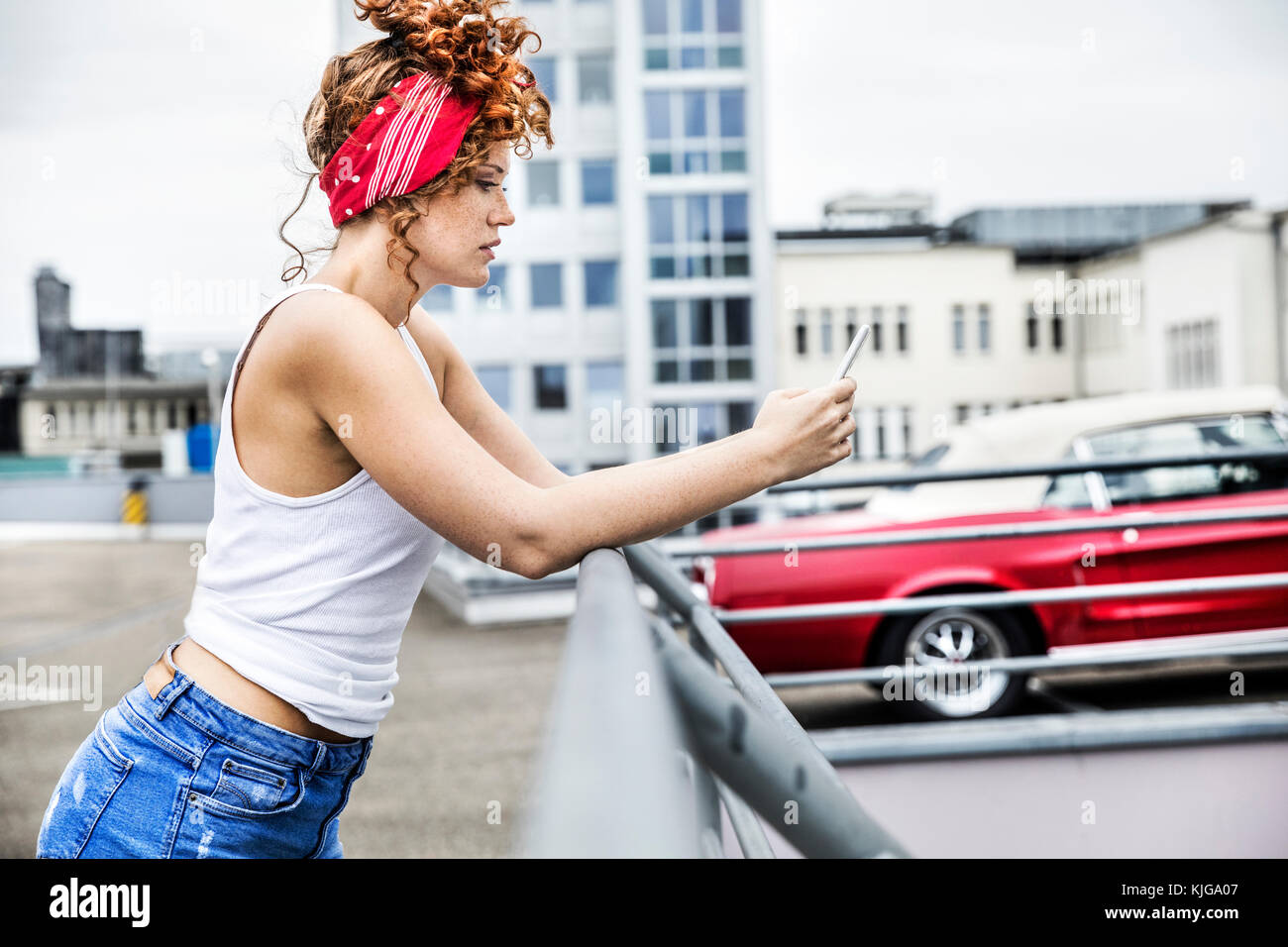 Redheaded donna sul parcheggio livello azienda telefono cellulare Foto Stock