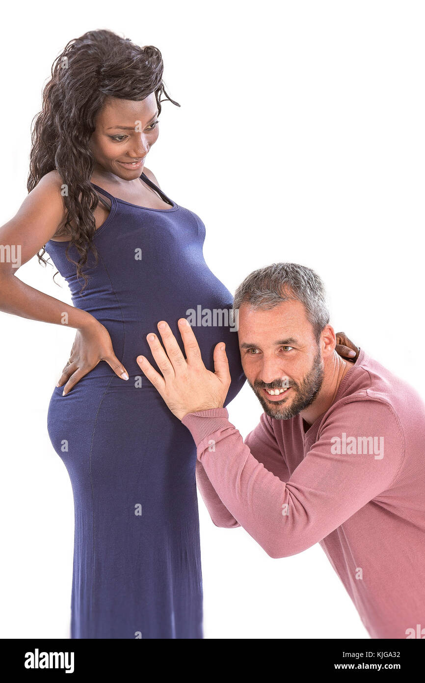 Famiglia giovane , uomo caucasico mettere il suo orecchio alla pancia del suo nero moglie incinta e ascolto feto heartbeat dell Foto Stock