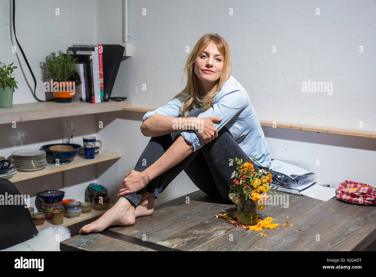 Donna bionda a casa seduti su un tavolo di legno Foto Stock