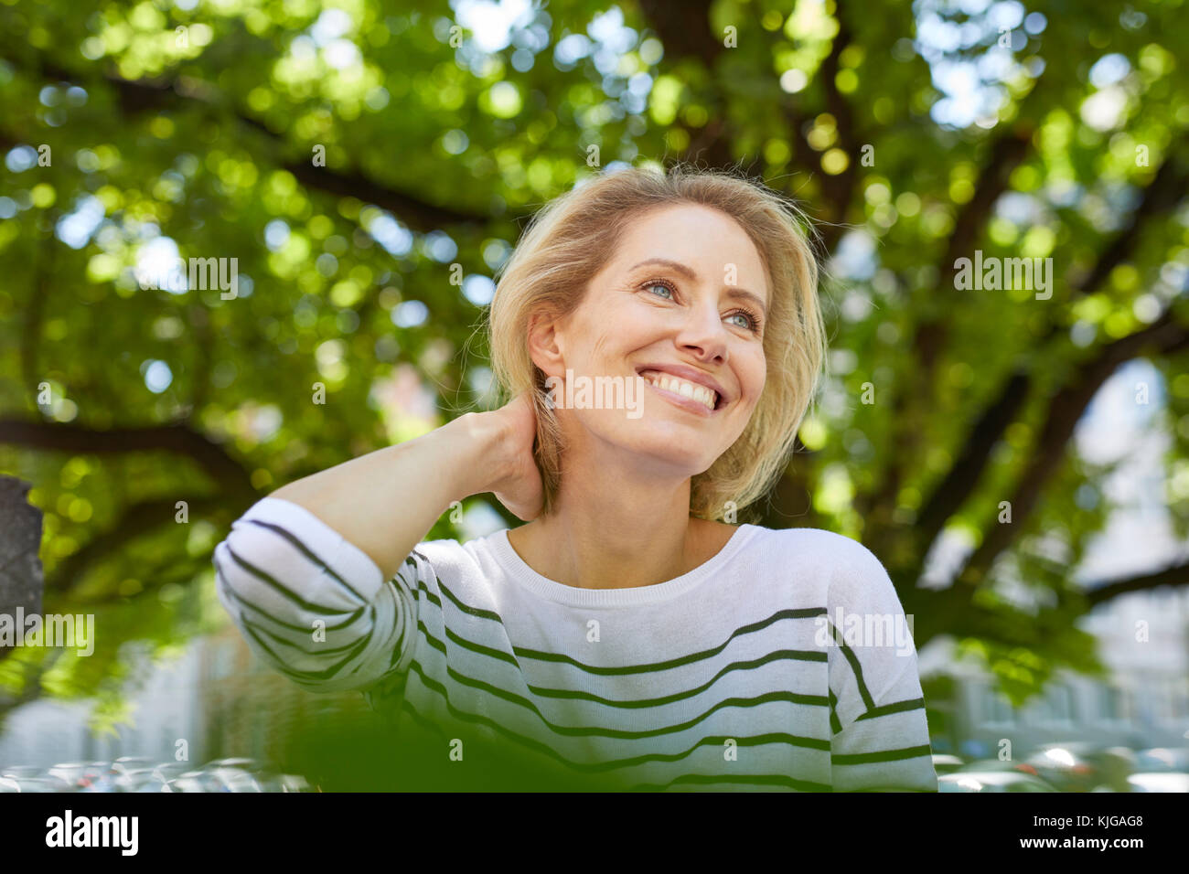 Ritratto di felice donna bionda di fronte a un albero Foto Stock